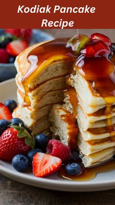 a stack of pancakes with syrup and fruit on the side