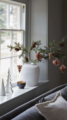 a white vase sitting on top of a window sill next to a christmas tree