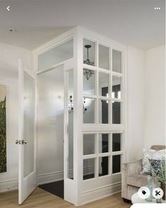 an open door leading into a living room with white walls and wood flooring on the side