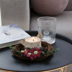 a candle is sitting on a table with a glass and some other items in front of it