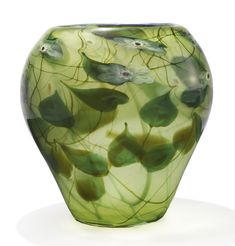 a green vase sitting on top of a white table covered in leaves and water lilies