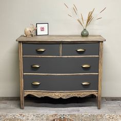 a grey dresser with gold handles and drawers on top of a rug next to a white wall