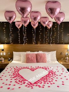 a bed with pink heart shaped balloons hanging from the headboard