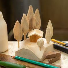 a wooden toy house sitting on top of a table next to pencils and markers