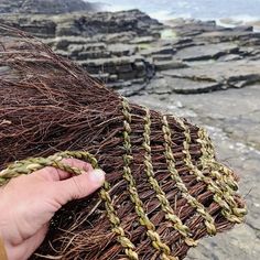 someone is holding some kind of fishing net on the rocks by the water's edge