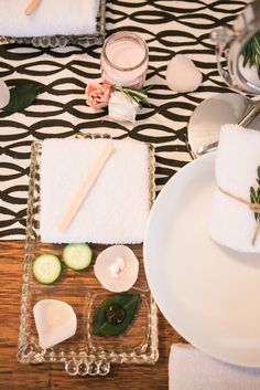 a table topped with plates and napkins covered in white towels next to cucumber slices