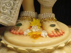 a cake with two feet on top of it, decorated with flowers and gold jewelry