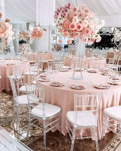 the tables are set with white chairs and pink centerpieces