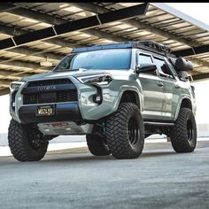 the toyota truck is parked in front of an overpassed parking garage with its lights on