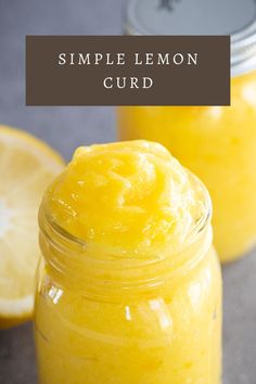 a jar filled with lemon curd sitting next to two slices of lemon on top of a table