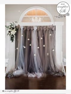 an arch with flowers and tulle hanging from it