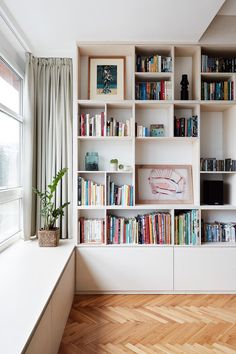 a bookshelf filled with lots of books next to a window