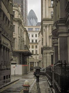 a person with an umbrella is walking down the street in front of some tall buildings