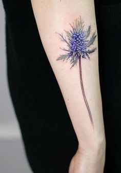 a woman's arm with a blue flower tattoo on the left side of her arm