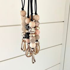 a bunch of beads hanging from a hook on a door handle with black cord and white background