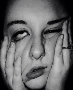 a black and white photo of a woman holding her hands to her face with one hand