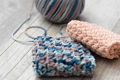 two crocheted items sitting next to each other on a wooden table with yarn