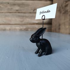 a small black rabbit figurine holding a sign