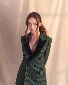 a woman in a green and black suit posing for the camera with her hands on her hips