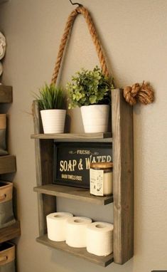 a wooden shelf with some plants and toilet paper on it next to a white toilet