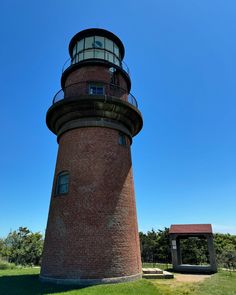 a large brick tower with a light house on it's side in the middle of a grassy area