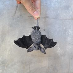 a person holding a small bat ornament in their hand