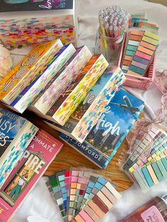 there are many different colored pencils and books on the table next to each other