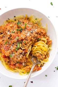 a white bowl filled with spaghetti and meat sauce