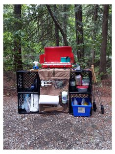 a picnic table with coolers and other items in the woods