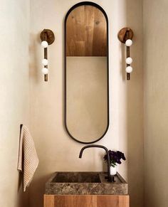 a bathroom sink sitting under a mirror next to a wall mounted faucet with lights on it