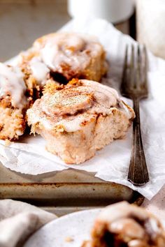 two cinnamon rolls sitting on top of paper next to a fork