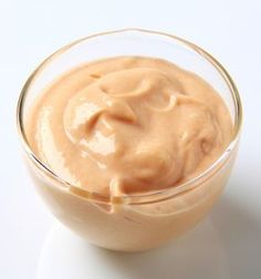 a glass bowl filled with sauce on top of a white table