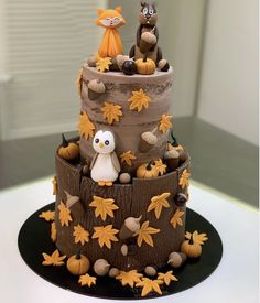 a three tiered cake decorated with animals and leaves