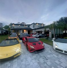 several different colored sports cars parked in front of a house