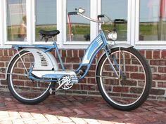 a blue and white bicycle parked in front of a brick building next to a window