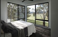 a bedroom with large windows and a bed in front of the sliding glass doors that lead out to a grassy field