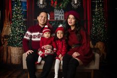 a family sitting on a couch in front of christmas decorations