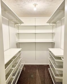 an empty walk in closet with white shelves and clear drawers on the bottom shelfs