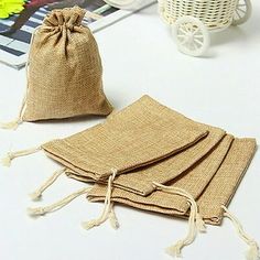 three burlap bags sitting on top of a table next to a flower vase