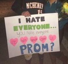 two people standing next to each other holding flowers and a sign that says, i hate everyone you not everyone prom