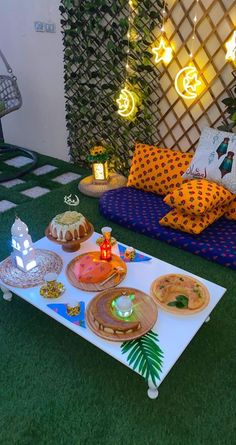 a table topped with lots of food on top of a lush green field covered in lights