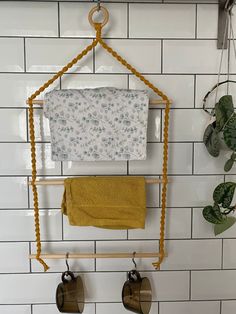 a towel rack with two towels hanging from it's hooks on a white tiled wall