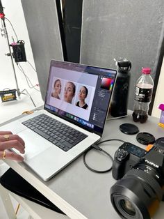 a laptop computer sitting on top of a desk next to a camera and other items