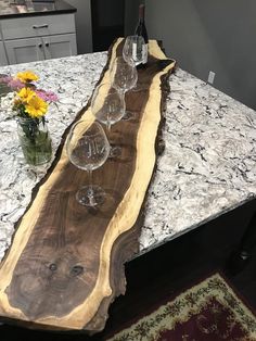 wine glasses are lined up on a table with a slab of wood in the middle