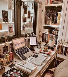 a laptop computer sitting on top of a desk next to a book shelf filled with books