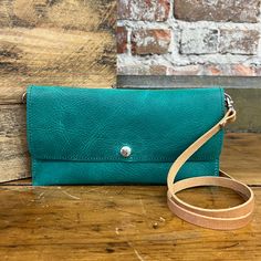 The Carly Clutch can be worn 5 ways - as a crossbody bag, a fanny pack, bum-bag, wallet or as a wristlet clutch. This small purse has a built-in wallet, with 3 card slots. The zippered pocket on the back will keep your small goods secure! 4.5" x 9" Single snap closure Removable 48" adjustable strap Removable wristlet One exterior zipper pocket Handcrafted in our workshop in Chariton, Iowa – USA Due to the resolution of your mobile and computer screens, actual color may vary. Our leather is premium full grain and may have occasional range markings. Green Crossbody Belt Bag For Everyday Use, Travel Wallet With Detachable Strap And Crossbody Shape, Clutch Wallets With Cell Phone Pocket For On-the-go, Crossbody Coin Purse With Cell Phone Pocket, Travel Clutch Belt Bag With Removable Pouch, Green Clutch With Removable Pouch For Everyday, Crossbody Coin Purse With Removable Pouch, Green Clutch With Detachable Strap For Everyday Use, Everyday Crossbody Wallets With Removable Pouch