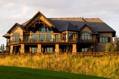 a large house sitting on top of a lush green field next to a tall grass covered hillside