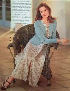 a woman is sitting on a wicker chair with her arms crossed and legs crossed