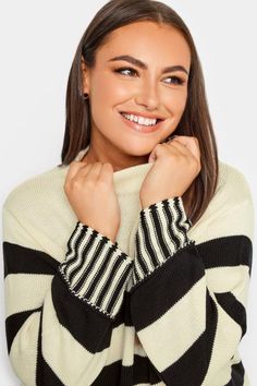 a woman with long hair wearing a black and white striped sweater smiling at the camera