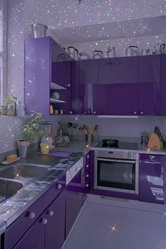 a kitchen with purple cabinets and lights on the ceiling is pictured in this image, it appears to be very colorful